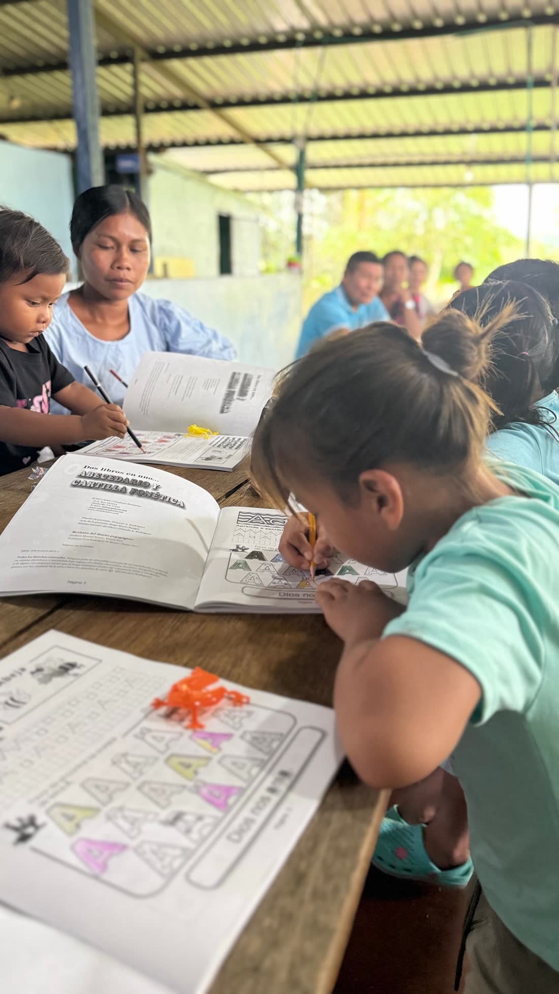 Una madre y sus hijos trabajando juntos en un cuadernillo de lectoescritura