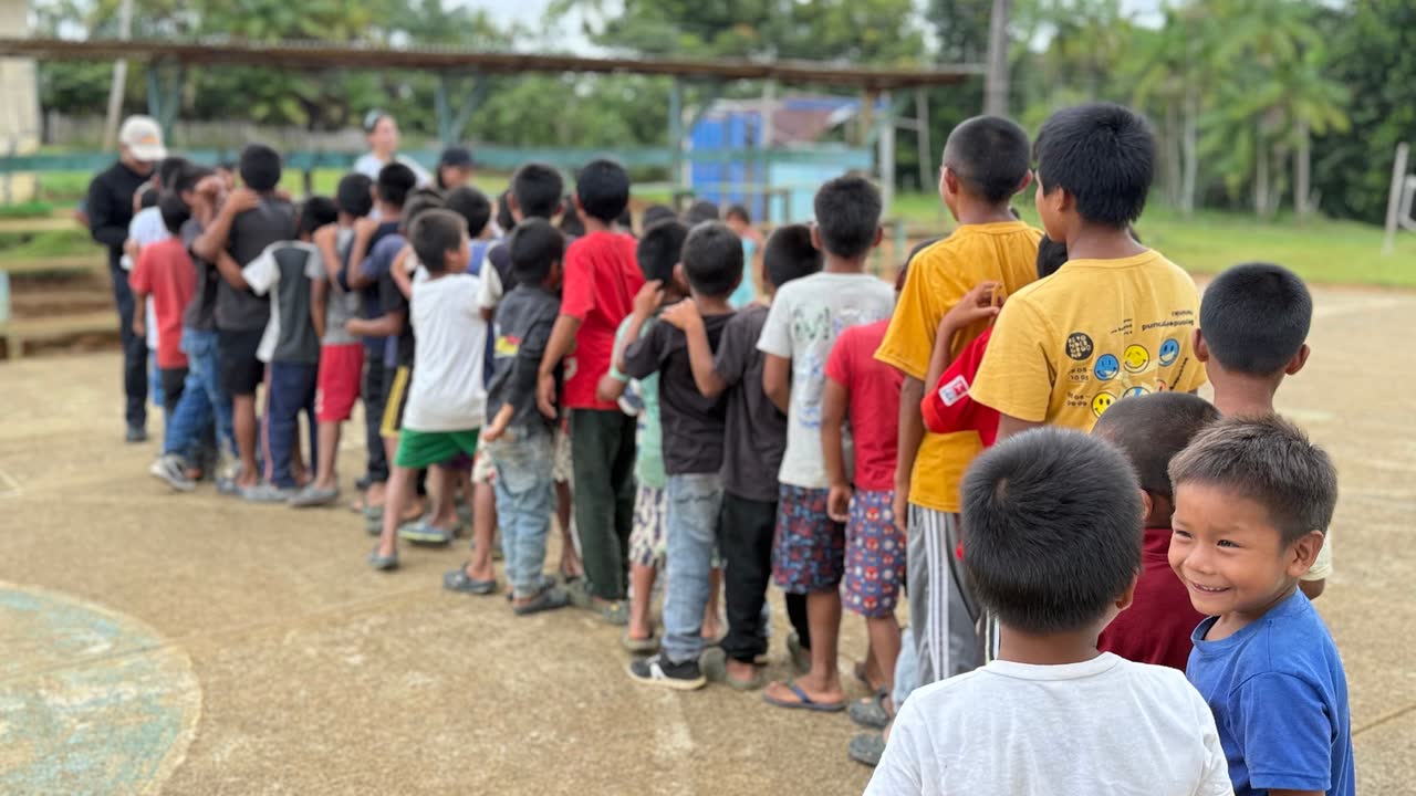 Una fila larga de niñas y niños esperando el inicio de la actividad