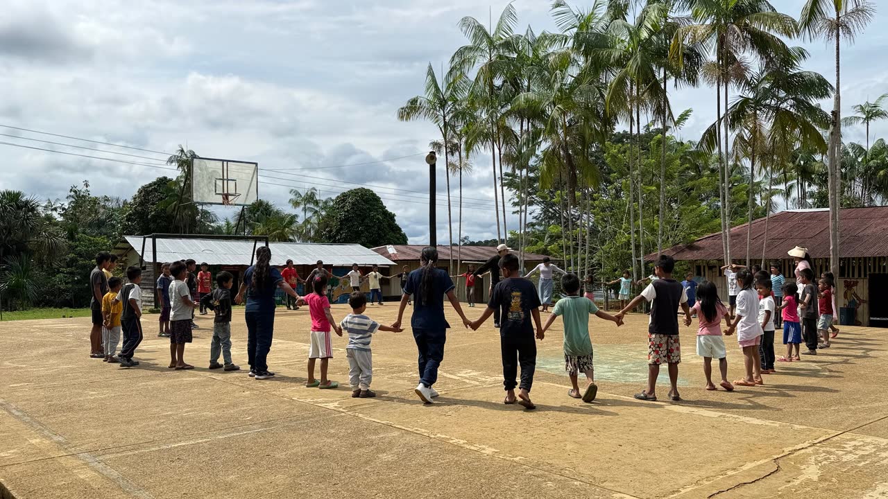 Niñas y niños tomados de la mano formando una ronda en una cancha